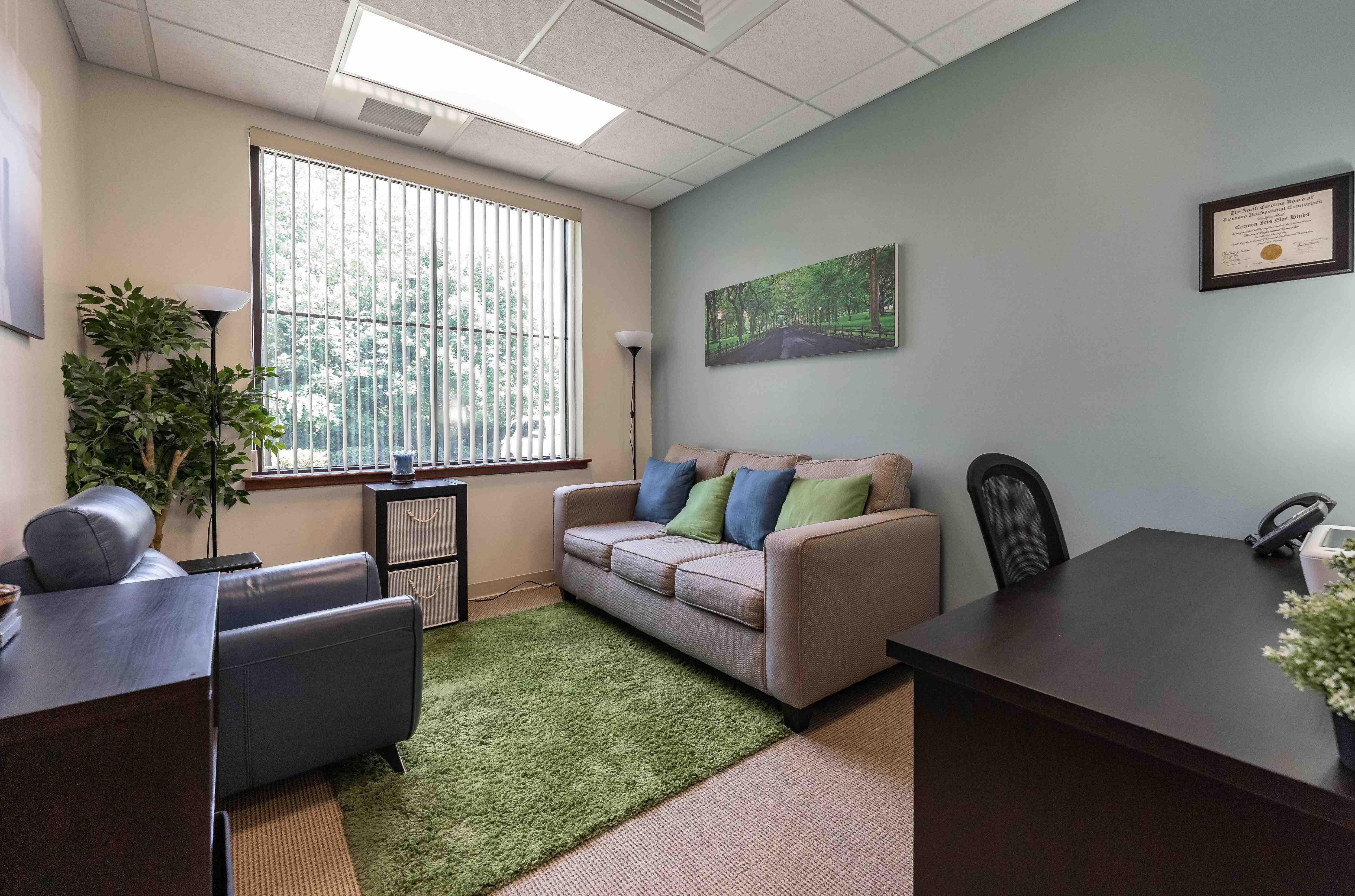 Private office with sofa, desk, and window